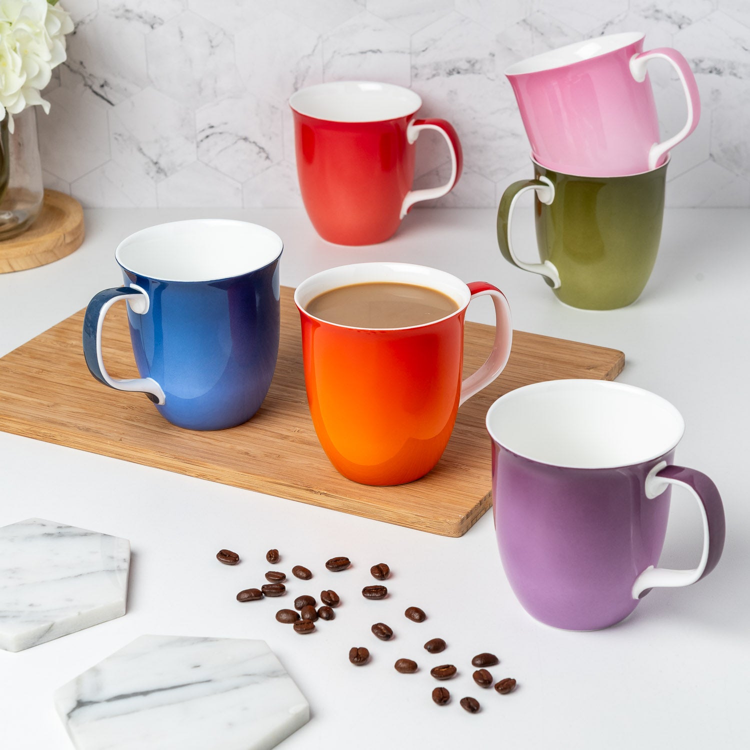 Colorful fine bone china Java mugs on a marble surface with coffee beans.